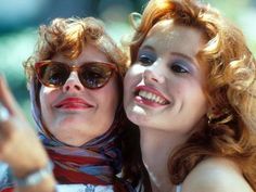 two women are taking a selfie with their cell phone while wearing sunglasses and scarves