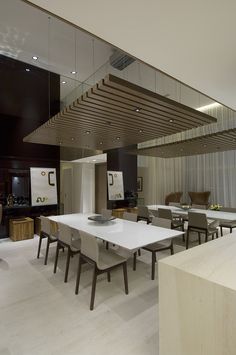 a large dining room with white tables and chairs in front of a wall mounted flat screen tv