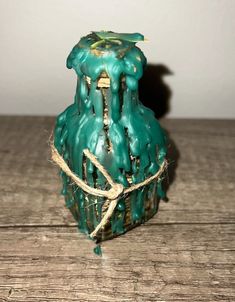 a green vase sitting on top of a wooden table next to a string tied around it