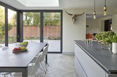 a kitchen with a table, chairs and an animal head on the wall behind it