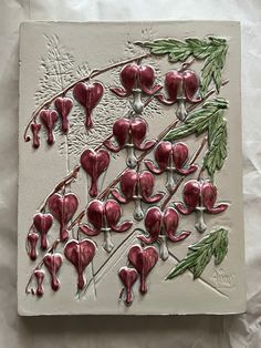 a ceramic artwork with red flowers and green leaves