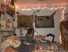 a woman sitting on top of a bed in a room filled with pictures and lights