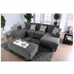 a living room with grey couches and pillows on the floor, coffee table in front of it