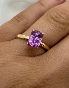 The Remi Ring (Solitaire) Remi, a Co-Founder of Other Half, was instantly drawn to this ring.  It is confident but classic, and as the biggest stone in the collection, it definitely makes a statement. Product Info: Natural (Unheated) Genuine Vibrant Pink Sapphire  1.42 Ct.  Emerald Cut  Solitaire   2mm - 18K Gold Band VS Clairty Please note: All our Sapphire gemstones are genuine and natural, meaning they were mined from the earth and left untreated.  This results in each gemstone having their o Classic Amethyst Promise Ring With Center Stone, Classic Yellow Gold Ruby Ring Gia Certified, Classic Yellow Gold Gia Certified Ruby Ring, Classic Gemstone Birthstone Ring For Promise, Timeless Sapphire Solitaire Promise Ring, Classic Ruby Ring For Promise With Prong Setting, Classic Promise Ring With Birthstone Gemstone, Classic Amethyst Ring For Gift, Classic Birthstone Ring For Promise