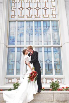 a bride and groom kissing in front of a stained glass window