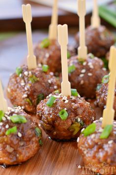 some meatballs with toothpicks in them sitting on a wooden board and ready to be eaten