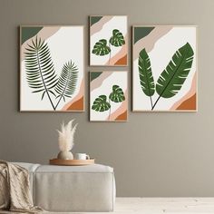 three green leaves are hanging on the wall above a white couch in a living room