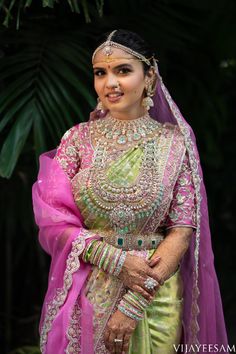 a woman in a pink and green bridal outfit with her hands on her hips