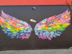 an artistic mural painted on the side of a garage door with colorful wings and circles