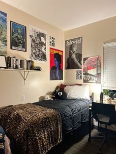 a bedroom with posters on the wall and a leopard print bed spread across the room