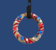 a red, white and blue wreath with stars hanging from it's side on a hook