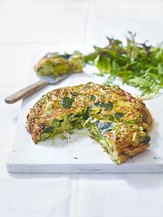 an omelet on a cutting board with a knife and salad in the background