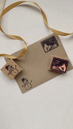 a couple of stamps on top of a piece of paper next to a brown ribbon