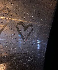 rain drops on the windshield of a car with a heart painted on it's side