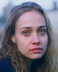 a close up of a person with long hair and blue eyes looking at the camera