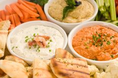 four bowls filled with different types of dips and veggies