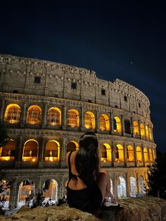 a woman sitting in front of the colossion at night