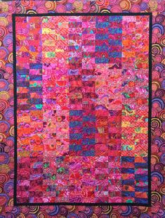 a pink and purple quilt with lots of different colored circles on it's sides