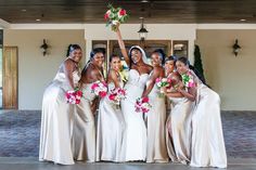 a group of women standing next to each other in front of a building holding bouquets