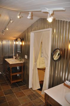 a bathroom with metal walls and tile flooring is shown in this image, there are lights on the ceiling