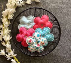 some fabric flowers are sitting in a wire basket next to white flowers on the floor