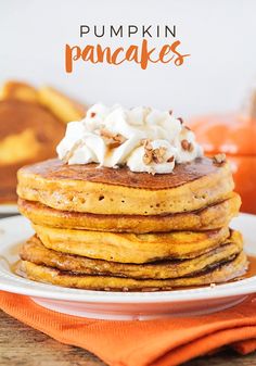 a stack of pumpkin pancakes with whipped cream on top and the words pumpkin pancakes above it