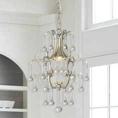 a chandelier hanging from the ceiling in a room with white walls and windows