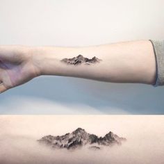 two mountains are shown on the arm and one has a small mountain tattoo on it