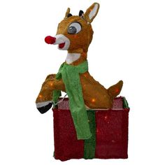 a lighted reindeer sitting on top of a red box with a green scarf around it's neck