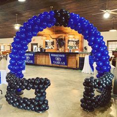 an arch made out of black and blue balloons in the middle of a banquet hall