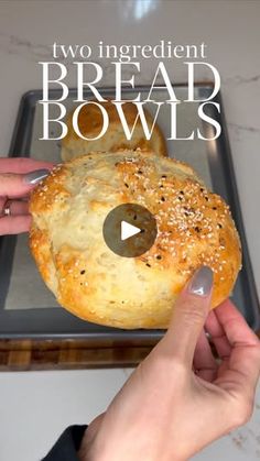 someone is holding a bagel in front of a baking sheet with the words two ingredient bread bowls on it