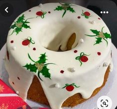 a white frosted cake with holly decorations on it