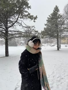 a woman is standing in the snow with her scarf around her neck and hat on