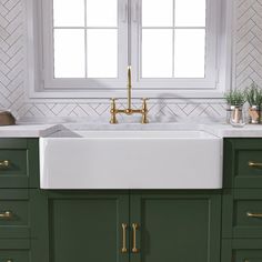 a kitchen with green cabinets and white counter tops, gold faucets and brass pulls