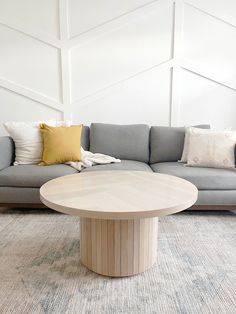 a living room with a couch, table and pillows on the floor in front of a white wall