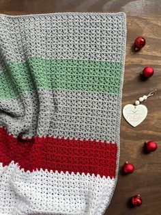 a crocheted blanket sitting on top of a wooden table next to christmas ornaments