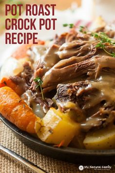 a plate full of meat and vegetables with gravy on top, sitting on a table