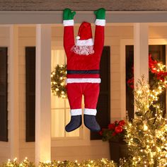 an inflatable santa clause hanging from the roof of a house with christmas lights around it