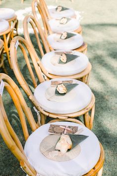 a row of wicker chairs with place settings on them