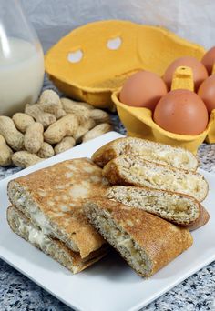 some food is on a white plate near eggs and almonds with a carton of milk in the background