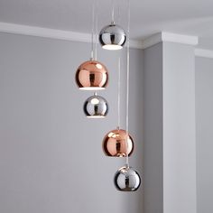 three chrome balls hanging from a ceiling in a room with grey walls and white trim