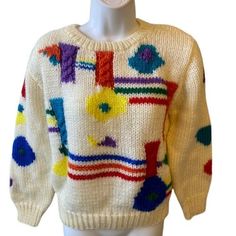 a white sweater with multicolored designs on the front and back, sitting on a mannequin's head