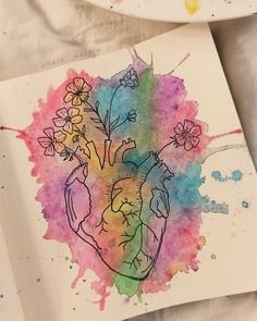 a drawing of a heart with flowers in it on a piece of paper next to a plate