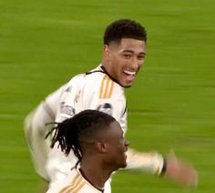 two young men are playing soccer on the field, one has his arm around the other's shoulder