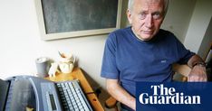 an older man sitting in front of a desk with a computer and keyboard on it