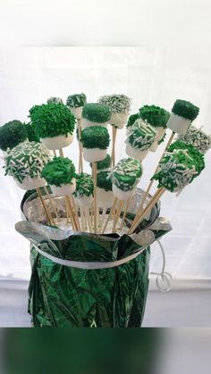 green cake pops with white frosting and sprinkles in a glass vase