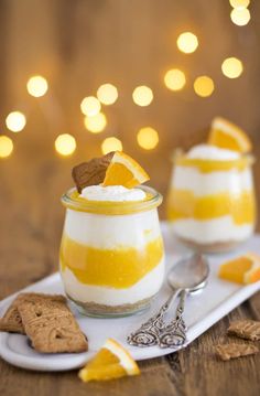 two desserts with orange slices and whipped cream on a white serving tray next to crackers