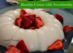 a cake with white frosting and strawberries on top is sitting on a glass plate