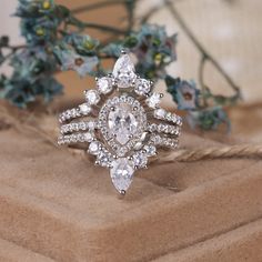 a diamond ring sitting on top of a piece of cloth next to some plants and flowers