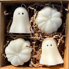 four white candles with ghost faces in a box